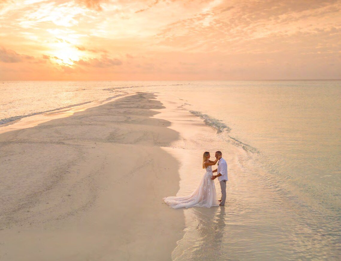 Couple walking along the Kuramathi sandbank at sunset